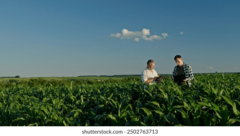 Two farmers from different generations collaborating in a cornfield, using a laptop. Concept of learning and knowledge transfer - Powered by Shutterstock