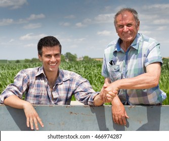 Two farmers shaking hands over trailer full of grains. Agriculture and farming concept