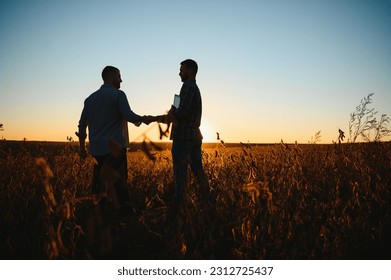Two farmers shaking hands in soybean field