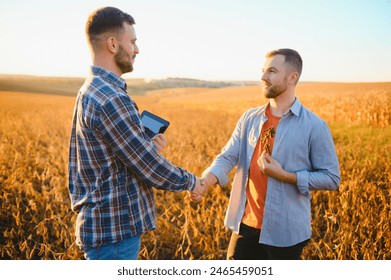 Two farmers shaking hands in soybean field - Powered by Shutterstock