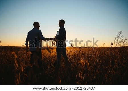 Two farmers shaking hands in soybean field