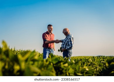 Two farmers in soy field making agreement with handshake. - Shutterstock ID 2338166517
