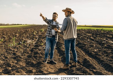 Two farmers standing in the field and using a digital tablet
