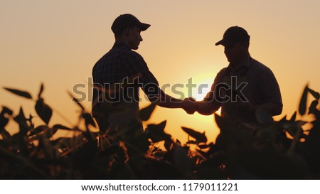 Two farmers talk on the field, then shake hands. Use a tablet 商業照片 © 