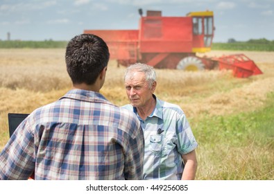 Two Farmers Talking On Wheat Field During Harvest