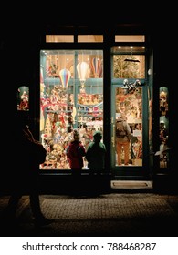 Two Fascinated Children In Front Of A Toy Store With Balloons At Night In Prague In Winter At Christmas