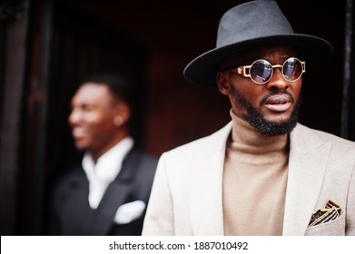 Two Fashion Black Men. Fashionable Portrait Of African American Male Models. Wear Suit, Coat And Hat.