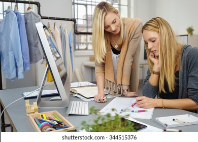 Two Fashion Stylist Women Sketching A New Design On A White Paper At The Table Inside The Office.