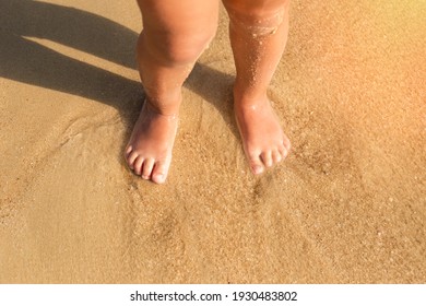 two feet, baby feet are on the sand, on the beach