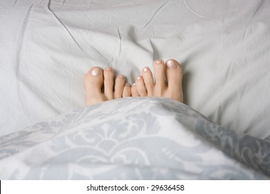 Two Feet Snuggled In A Duvet For Warmth,  Shot Landscape