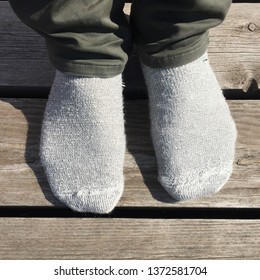 two feet in thick socks on wooden deck during spring in sweden 