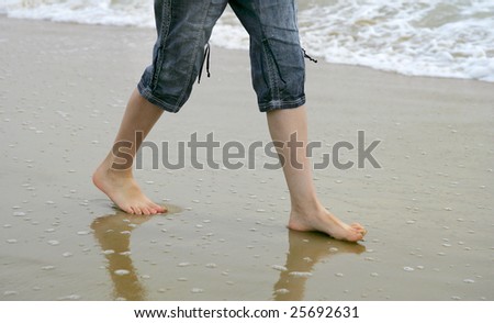 two feet walking along the beach near the water