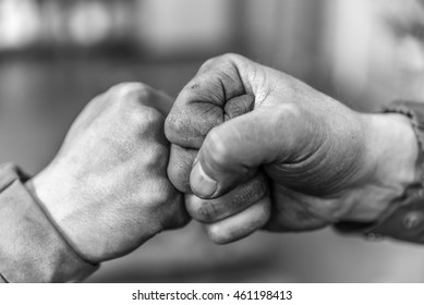 Two fellow workers greeting each other with a handshake using their fists as a symbol of companionship, friendship and solidarity.