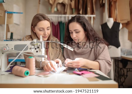 two femail Dressmakers or tailors or fashiondesigners or seamstresses woman working with sewing machine atv workshop studio. Small handmade business concept