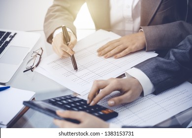Two female accountants counting on calculator income for tax form completion hands close-up. Business and audit concept