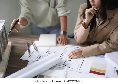 Two female architects discuss and brainstorm about building model and interior design on blueprint. - Powered by Shutterstock