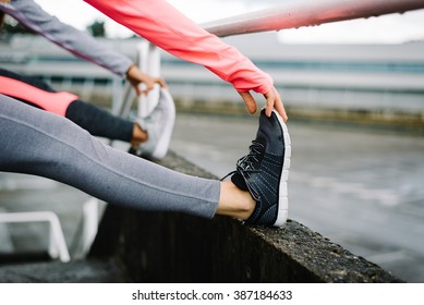 Two Female Athletes Stretching Legs And Exercising. Sporty Fitness Women Doing Warm Up Workout Before Training.