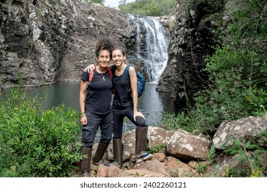 Two female backpackers smiling while enjoying exploring nature together.