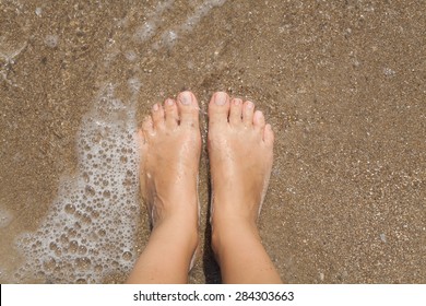 Two Female Bare Feet On Wet Sand In The Sea Foam