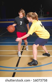 Two Female Basketball Players Compete In Gym