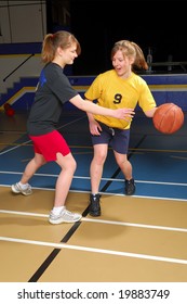 Two Female Basketball Players Scrimmage In School Gym.