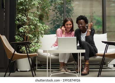 Two female colleagues are discussing some new business plans while sitting in the foyer of the company's building.