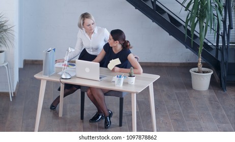 Two female colleagues talking in office - Shutterstock ID 1097878862