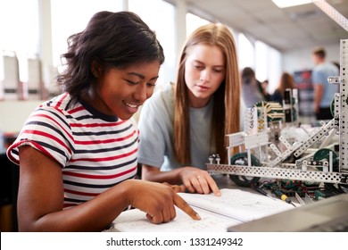 Two Female College Students Building Machine In Science Robotics Or Engineering Class