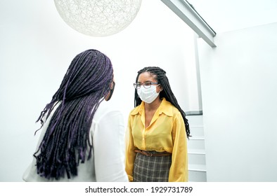 Two Female Coworkers Wearing Face Masks Greet Each Other Without Physical Contact. Concept Of Social Distance In The New Normal.