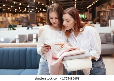 Two female customers examining cotton towels on sale at furnishings store