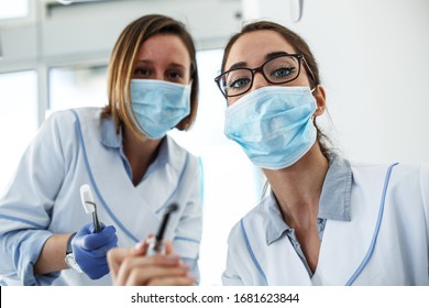 Two Female Dentist In Dental Office Examining Patient Teeth.Camera Angle From Patients Perspective.	