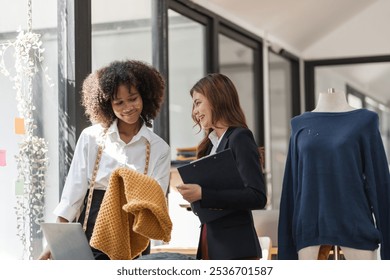 Two Female Designers Collaborating on Shirt Designs in a Modern Studio Environment with Mannequin and Fabric Samples - Powered by Shutterstock