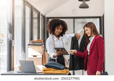 Two Female Designers Collaborating on Shirt Designs in a Modern Studio Environment with Laptops and Fabric Samples - Powered by Shutterstock