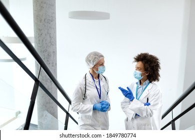 Two female doctors discussing while standing in a hallway at medical clinic and wearing protective face masks and gloves due to COVID-19 pandemic.  - Powered by Shutterstock