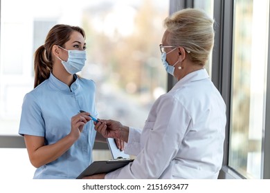 Two female doctors discussing while standing in office. Epidemic. Covid-19.