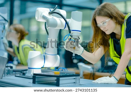 Two female engineering students in a high-tech university lab collaborate on a robotics project, learning hands-on programming skills for the future of industrial automation.