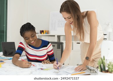 Two female fashion designer working together in tailor shop. Group of female dressmaker discuss fabric, pattern and sketch in sewing workshop - Powered by Shutterstock