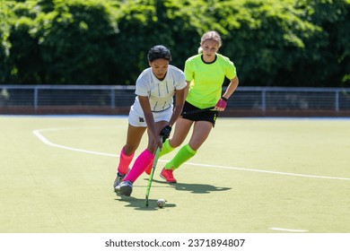 Two female field hockey players fighting for the ball on the pitch in attack. - Powered by Shutterstock