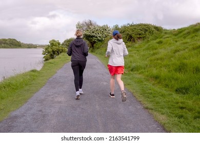Two female friend running in a park, Sport and fitness concept. Women jogging on a small pathway.