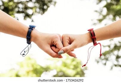 Two Female Friends Doing Fist Bump Outside In Summer Day