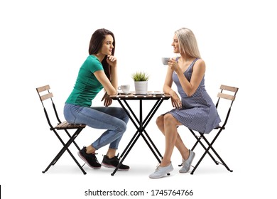 Two Female Friends Drinking Coffee And Sitting At A Wooden Table Isolated On White Background