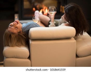 Two Female Friends Drinking Wine And Talking By A Fire Place. Life Stile Concept