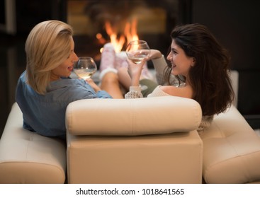 Two Female Friends Drinking Wine And Talking By A Fire Place. Life Stile Concept