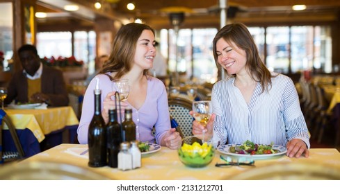 Two Female Friends Drinking Wine And Chatting During Meeting In Restaurant.