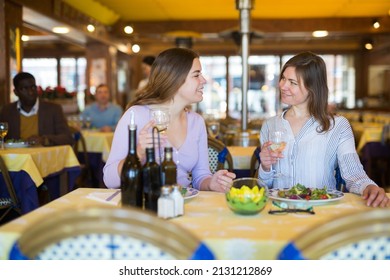 Two Female Friends Drinking Wine And Chatting During Meeting In Restaurant.