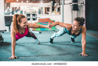 Two Female Friends Exercising Together In The Gym