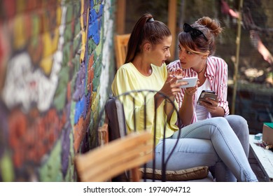 Two female friends gossip while sitting in a relaxed atmosphere in the bar. Leisure, bar, friendship, outdoor - Powered by Shutterstock