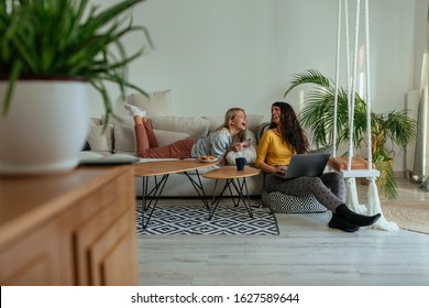 Two female friends hanging at living room during weekend