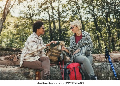 Two female friends hiking in nature enjoying take a tea break in a beautiful sunny autumn day. - Powered by Shutterstock