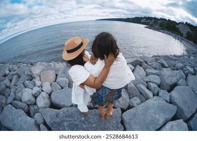 two female friends hugging on a rocky beach looking at the lake. Scene is warm and loving - Powered by Shutterstock